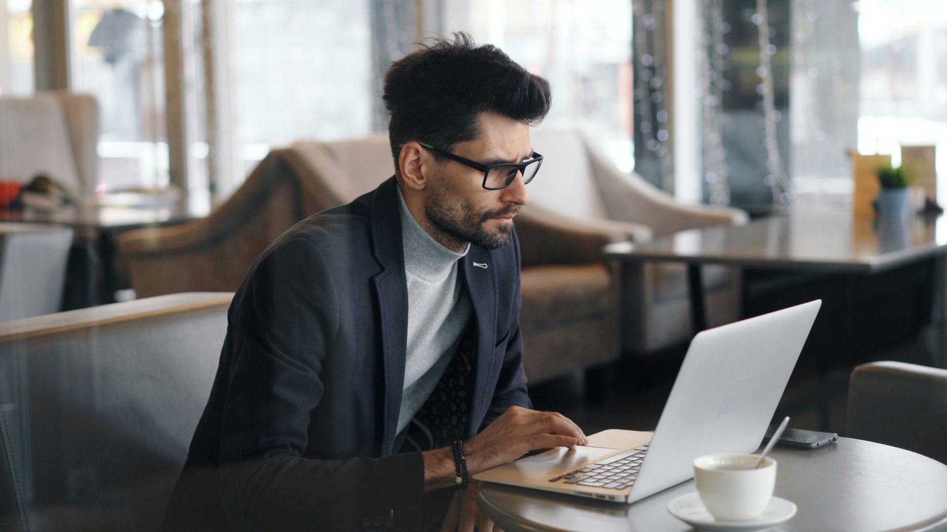 a man sitting at a table using a laptop computer