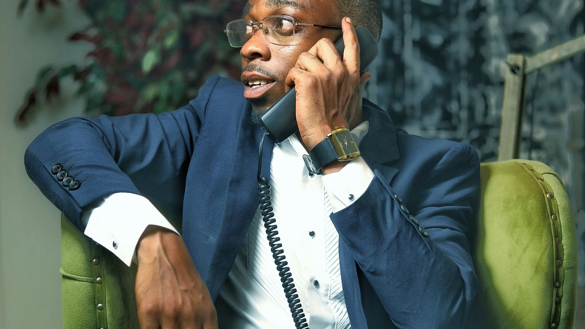 A man sitting in a chair talking on a cell phone