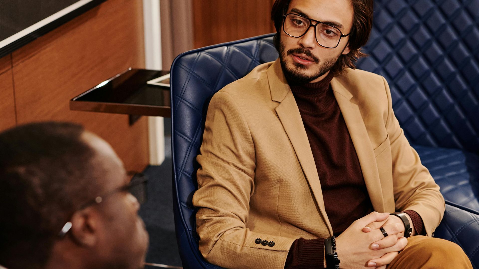 Two men in business attire engaged in a conversation in a modern office space.