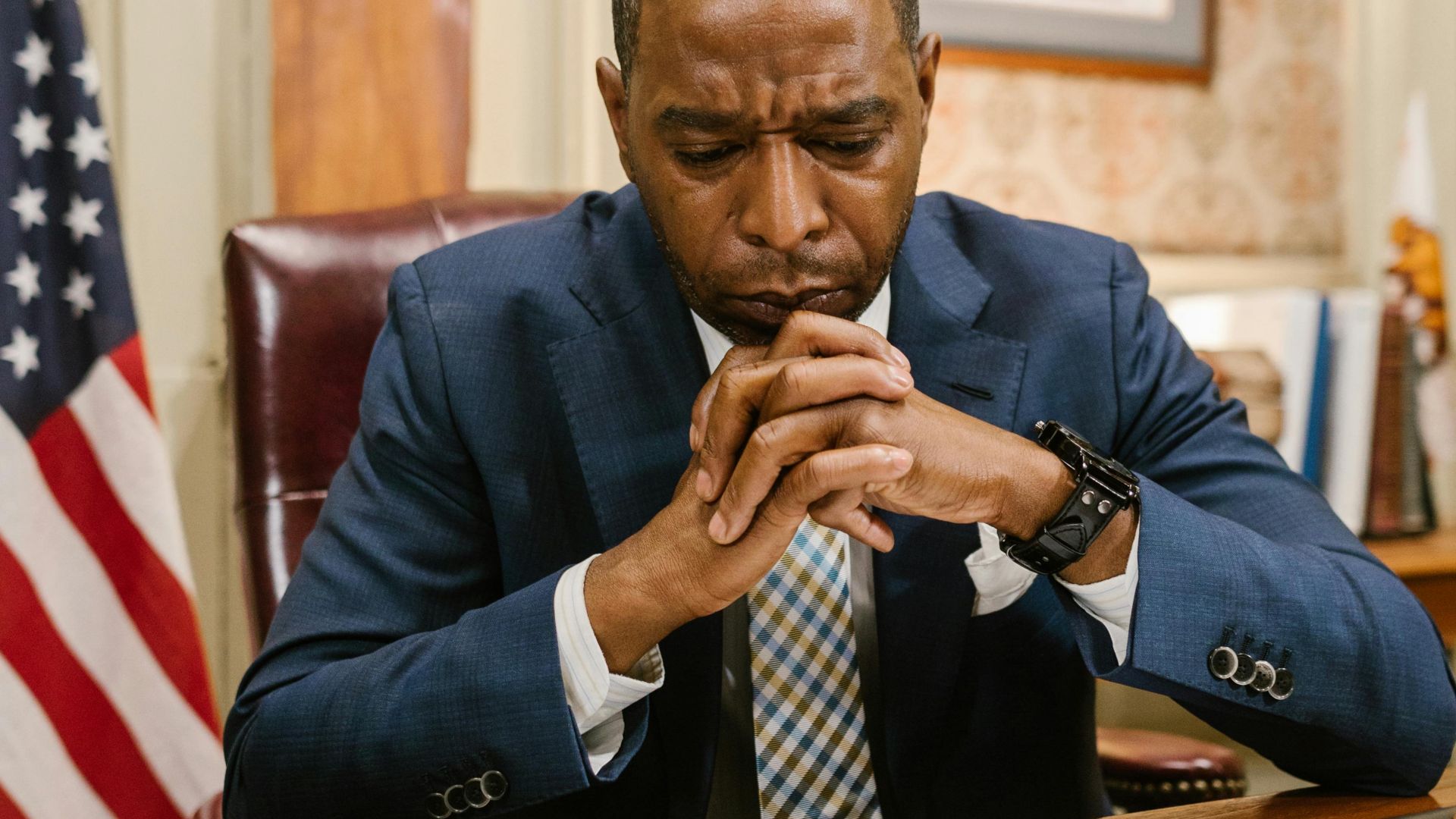 Lawyer in deep thought at office desk with documents and flag.