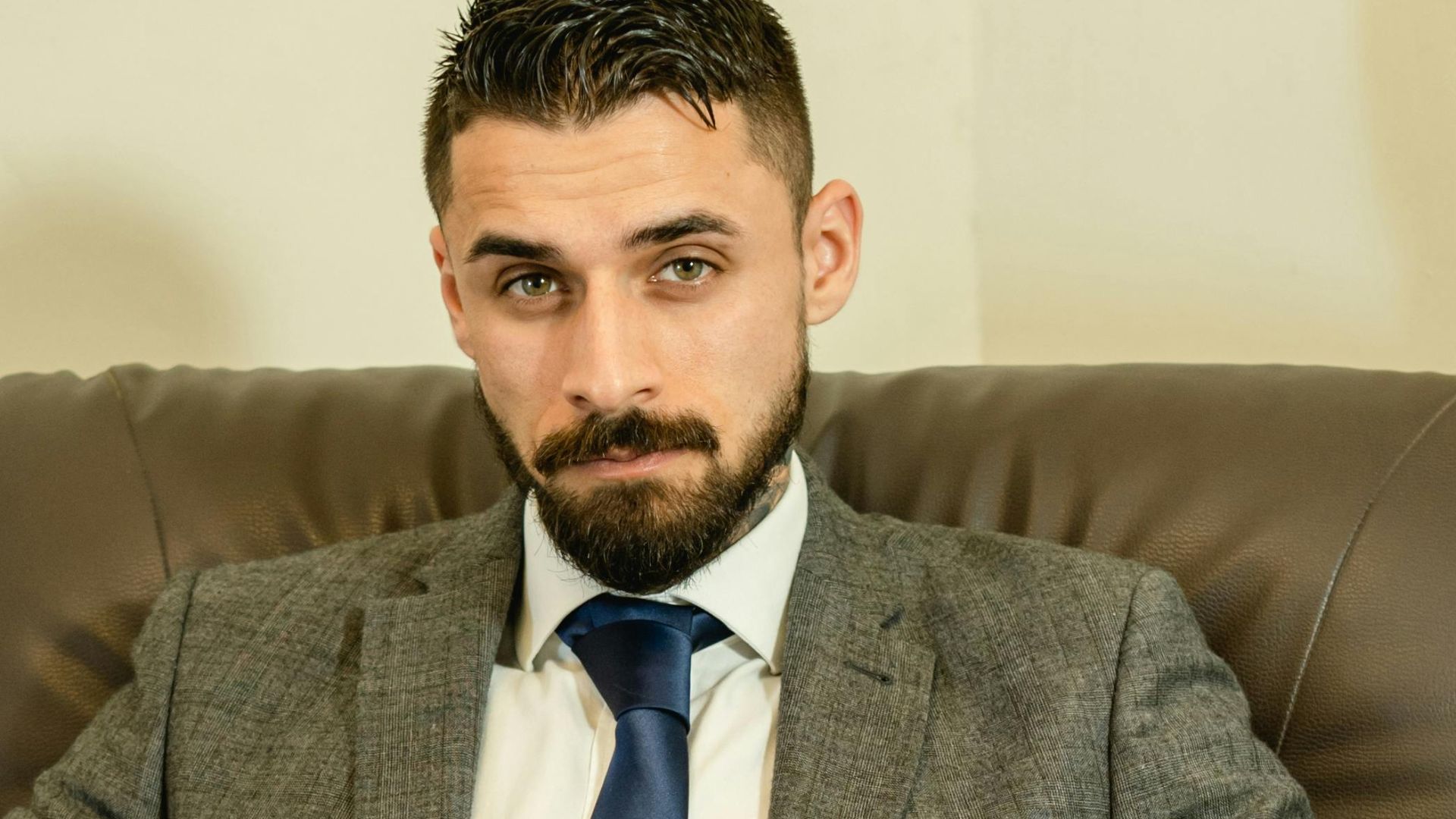 Confident business professional in gray suit with laptop in an office setting.