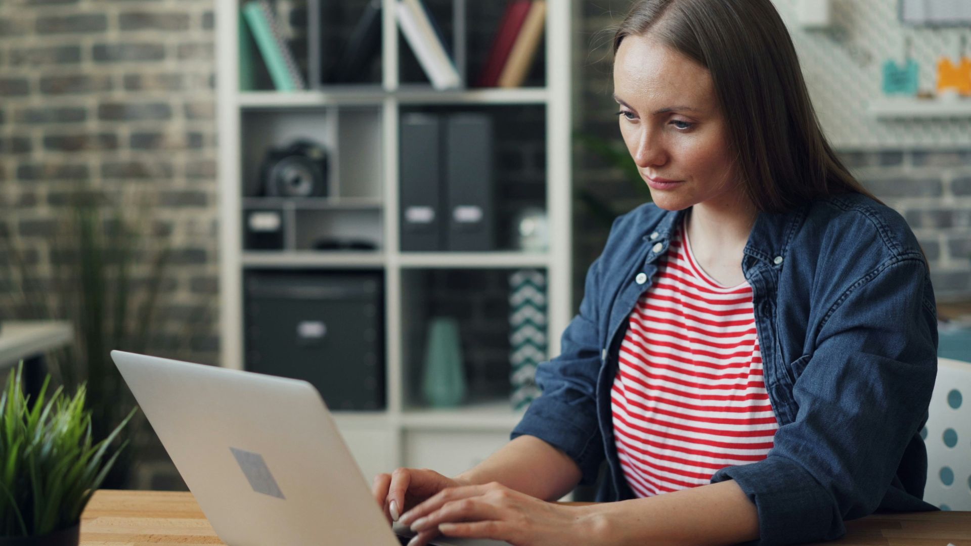 a woman sitting at a table using a laptop computer