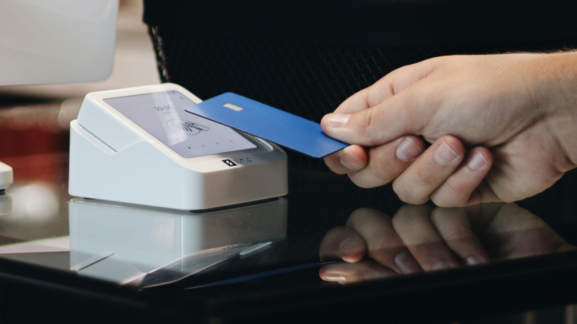 A person holding a credit card in front of a computer
