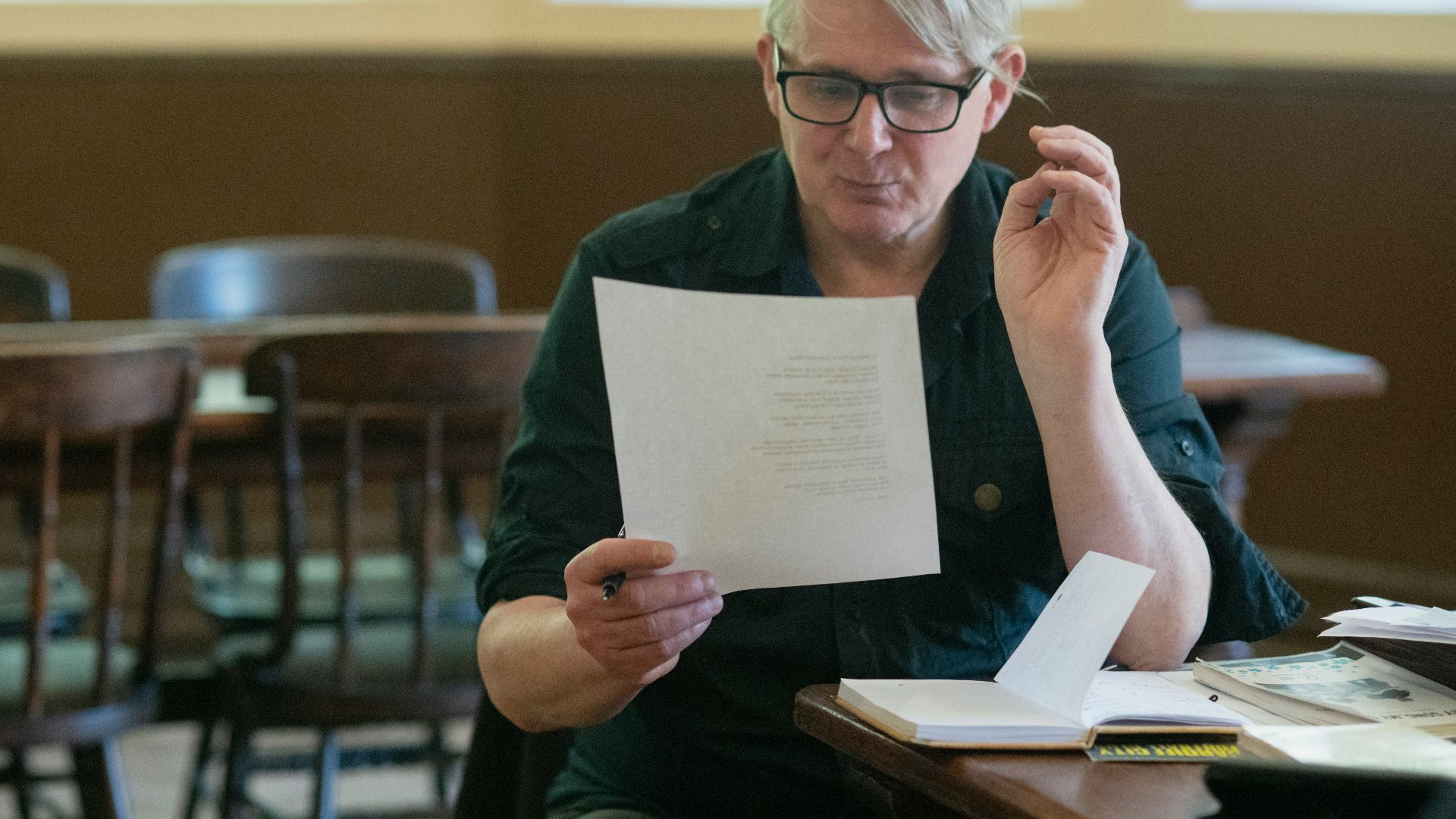 a man sitting at a table holding a piece of paper