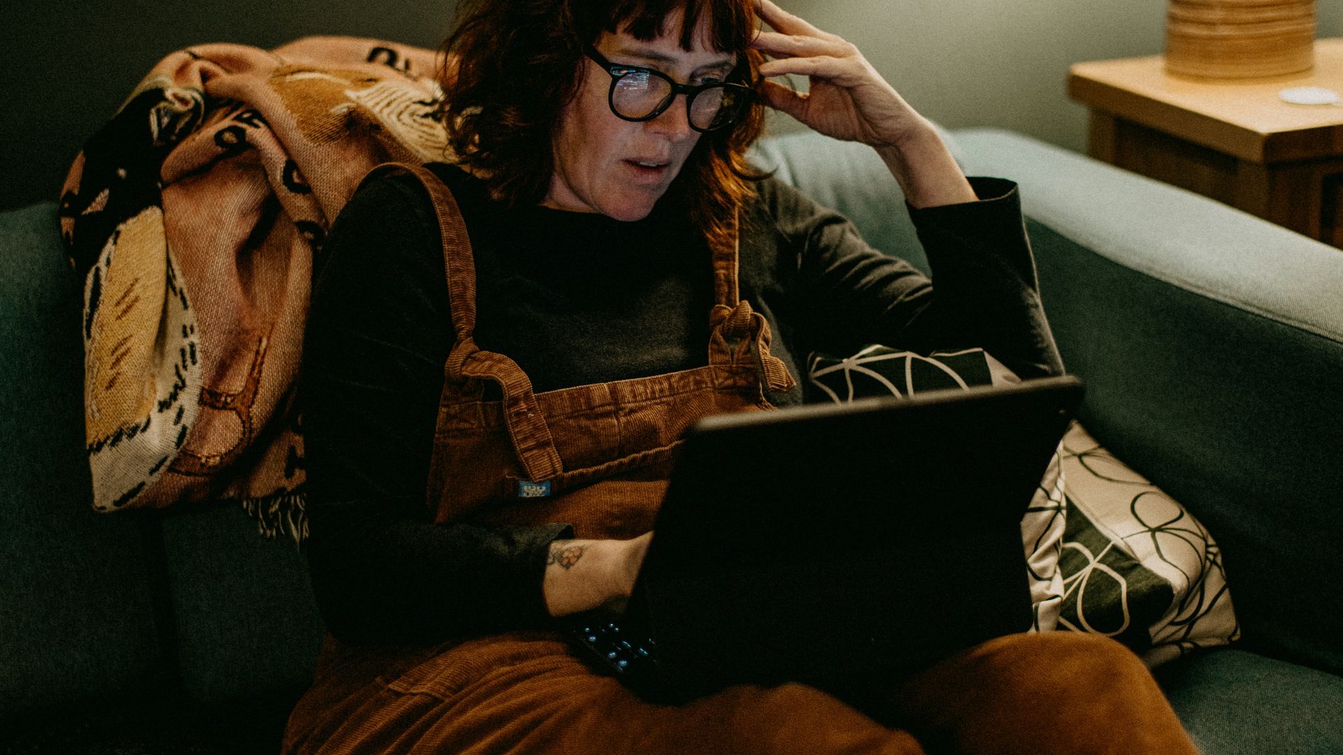 a woman sitting on a couch using a laptop computer