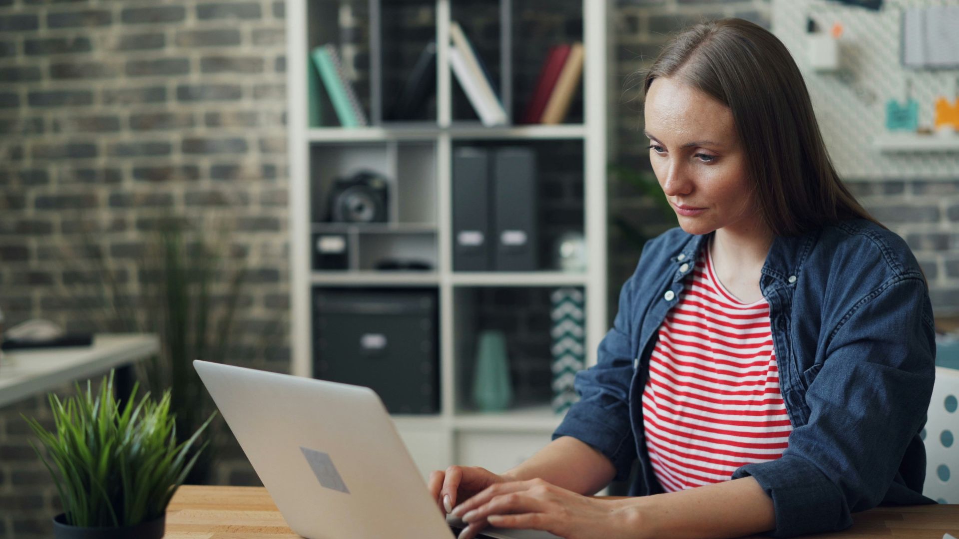 a woman sitting at a table using a laptop computer