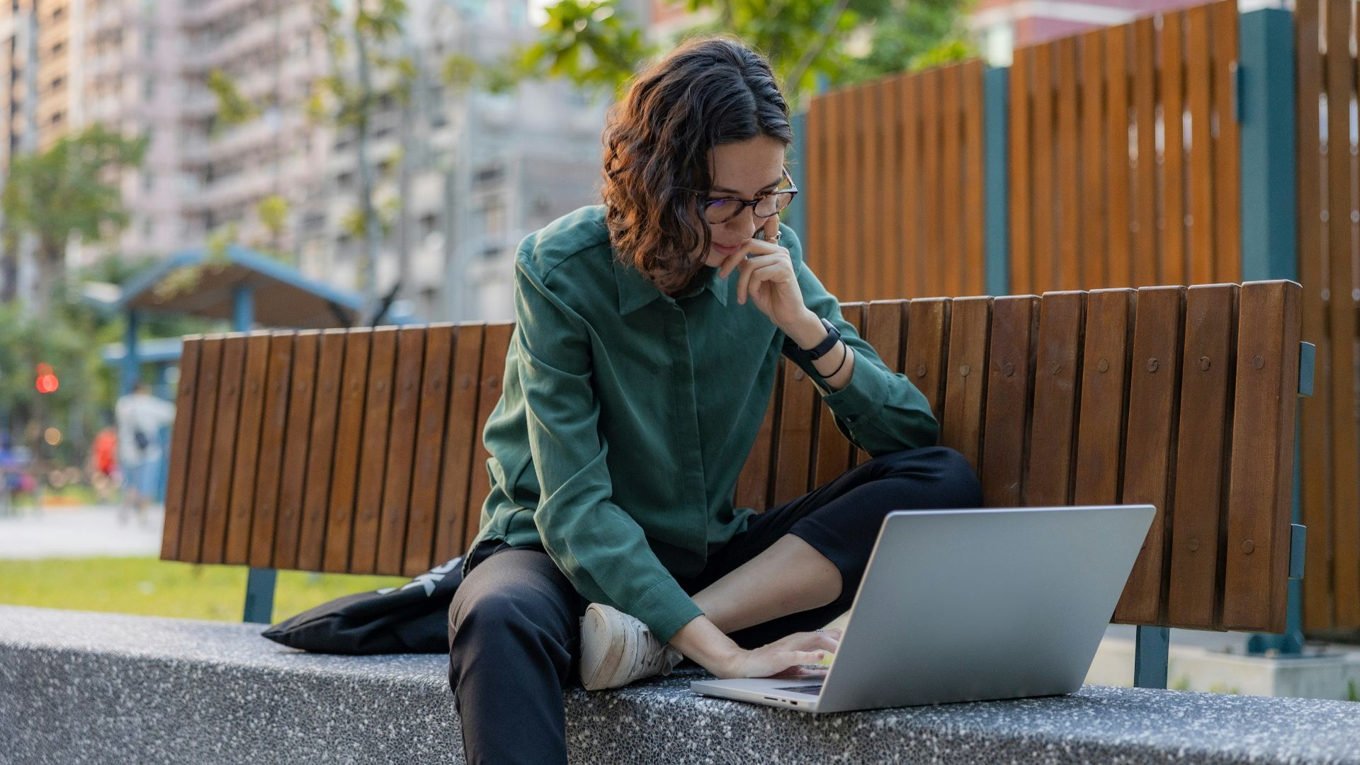 a woman sitting on a bench using a laptop computer