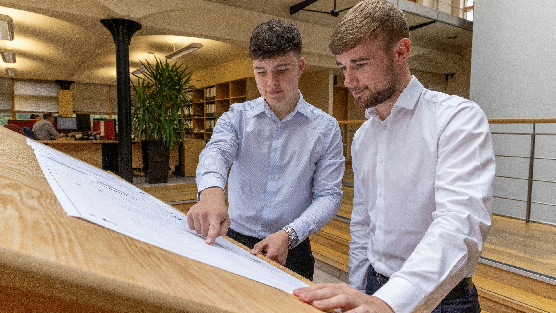 two men looking at a piece of paper on a table