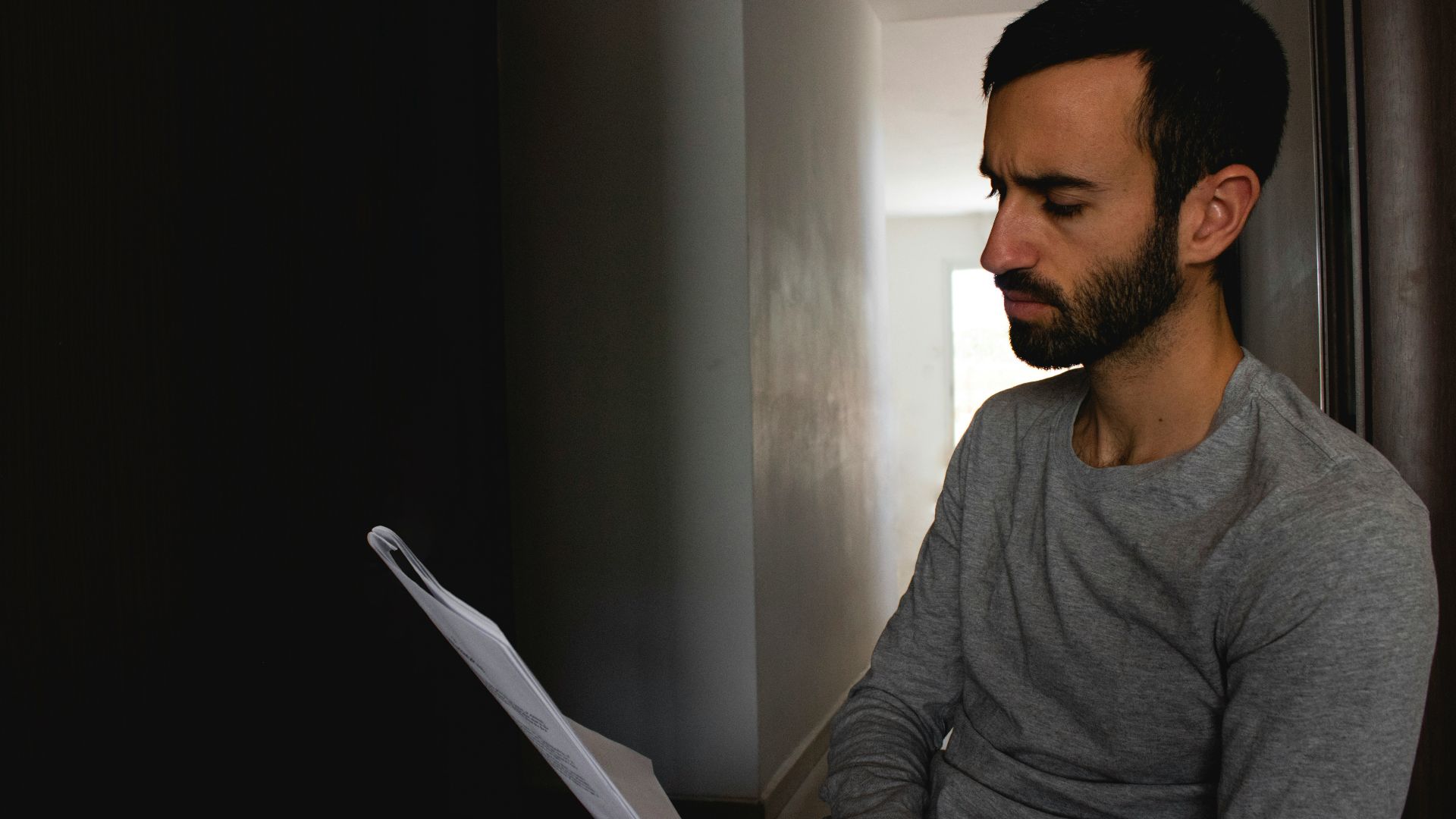 man in gray crew neck shirt holding white printer paper