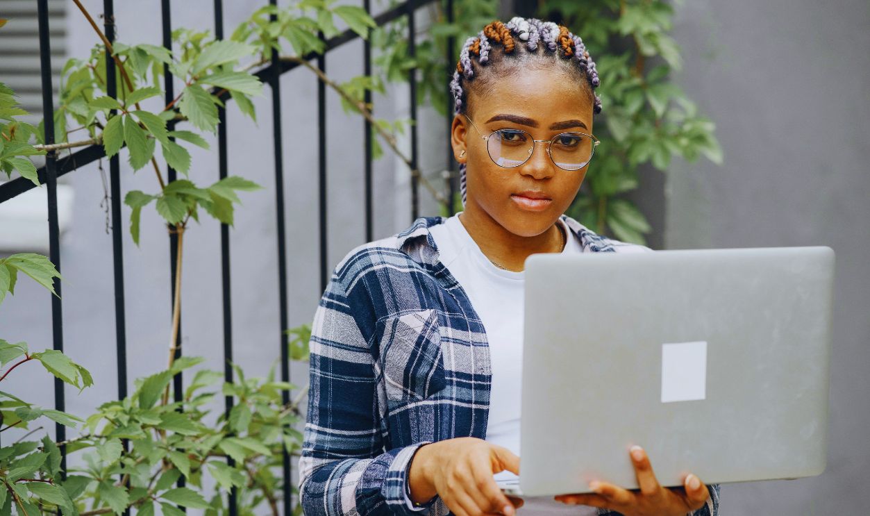 Woman Standing Outdoors Holding Open Laptop