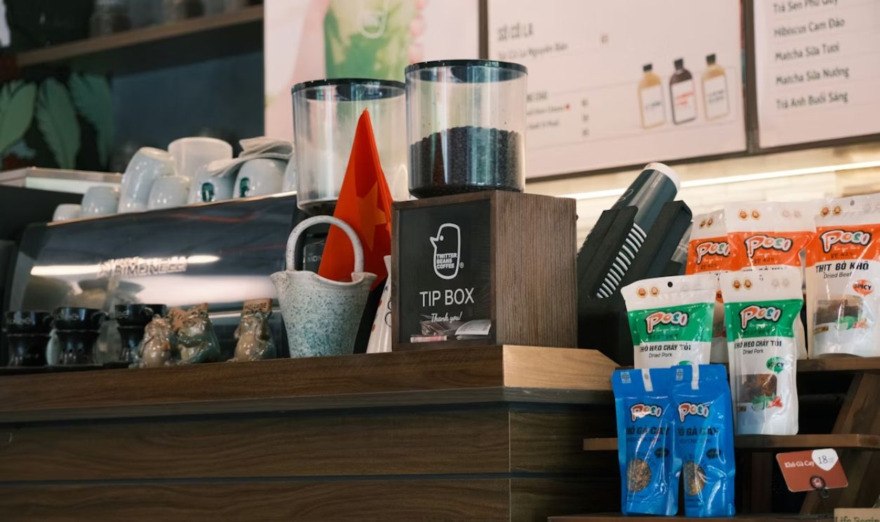 A coffee shop counter with supplies and tip jar.