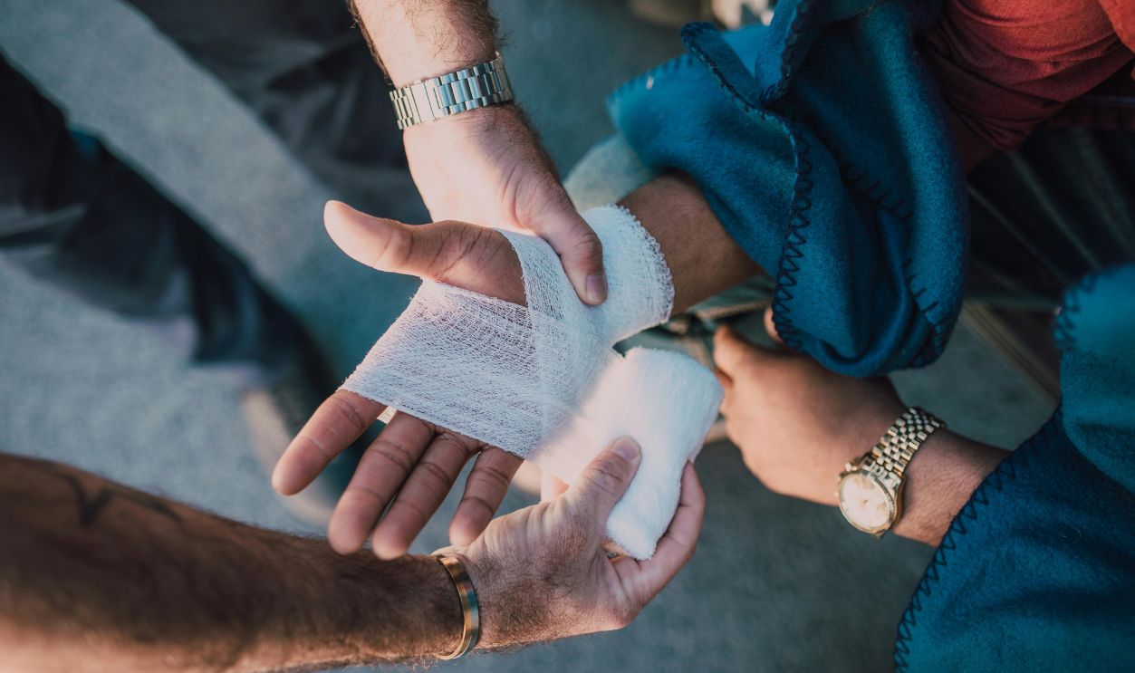 Person Applying Bandage on Another Person's Hand