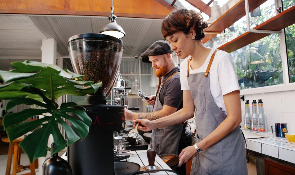 Baristas preparing coffee in machines in cafe kitchen