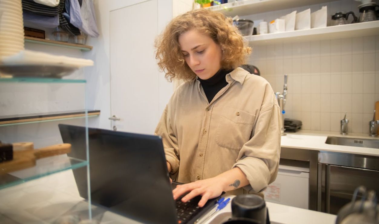 Woman in Beige Long Sleeves Using a Laptop