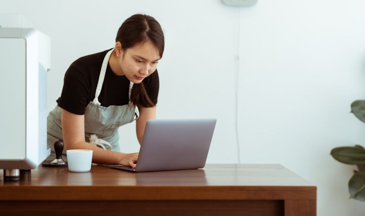 Focused woman in apron using laptop