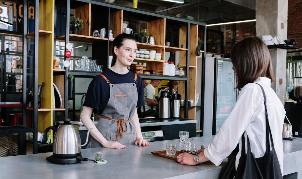Man in Black and Gray Crew Neck T-shirt Standing Beside Table