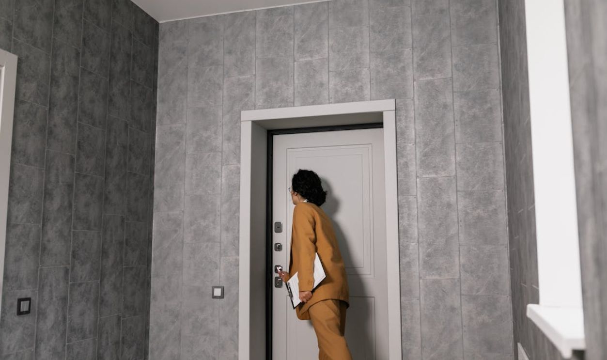 A Woman in Brown Suit Opening a Door
