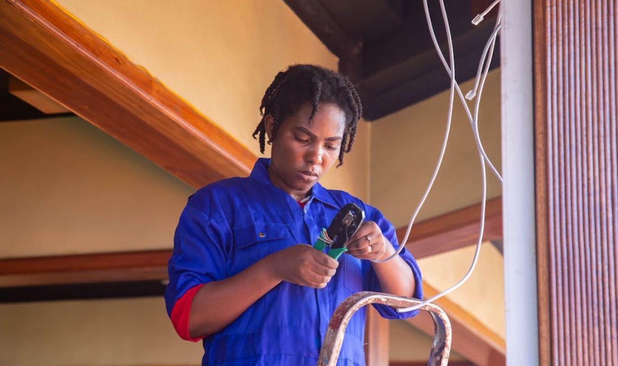 A Female Electrician Standing on a Ladder and Holding Cables