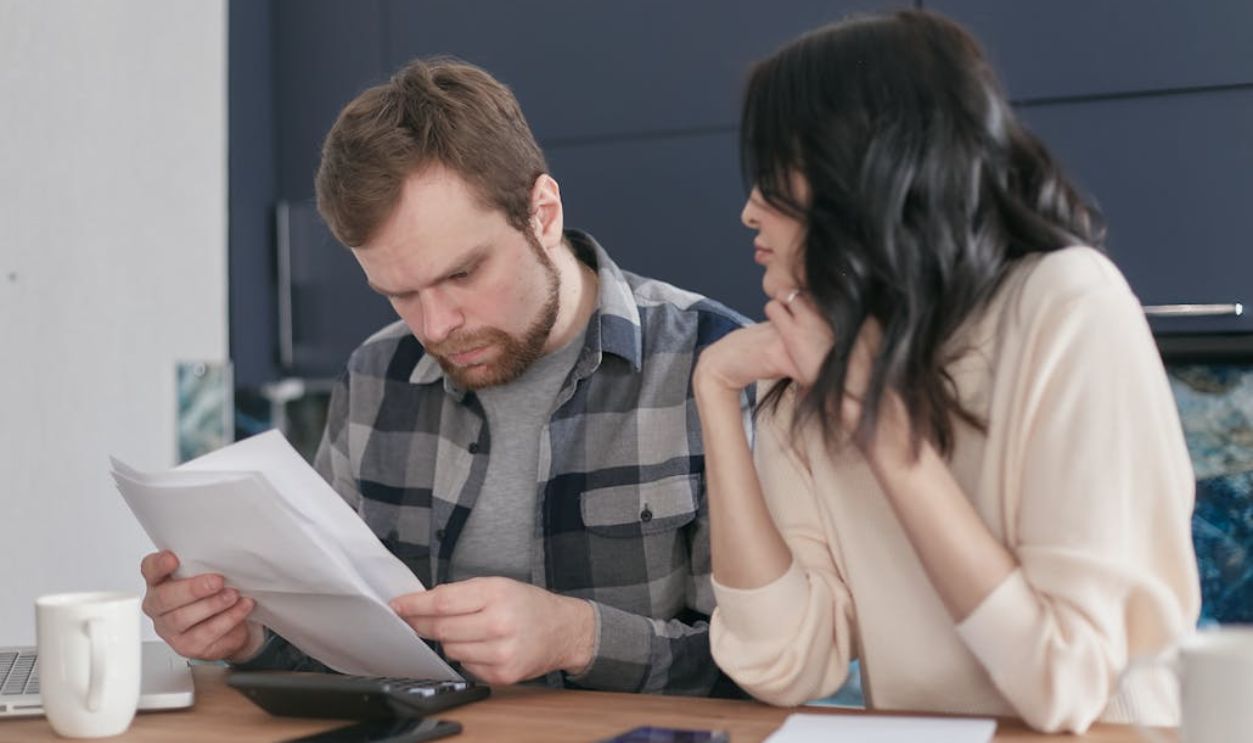 A Man Looking at Papers Sitting Besides a Woman