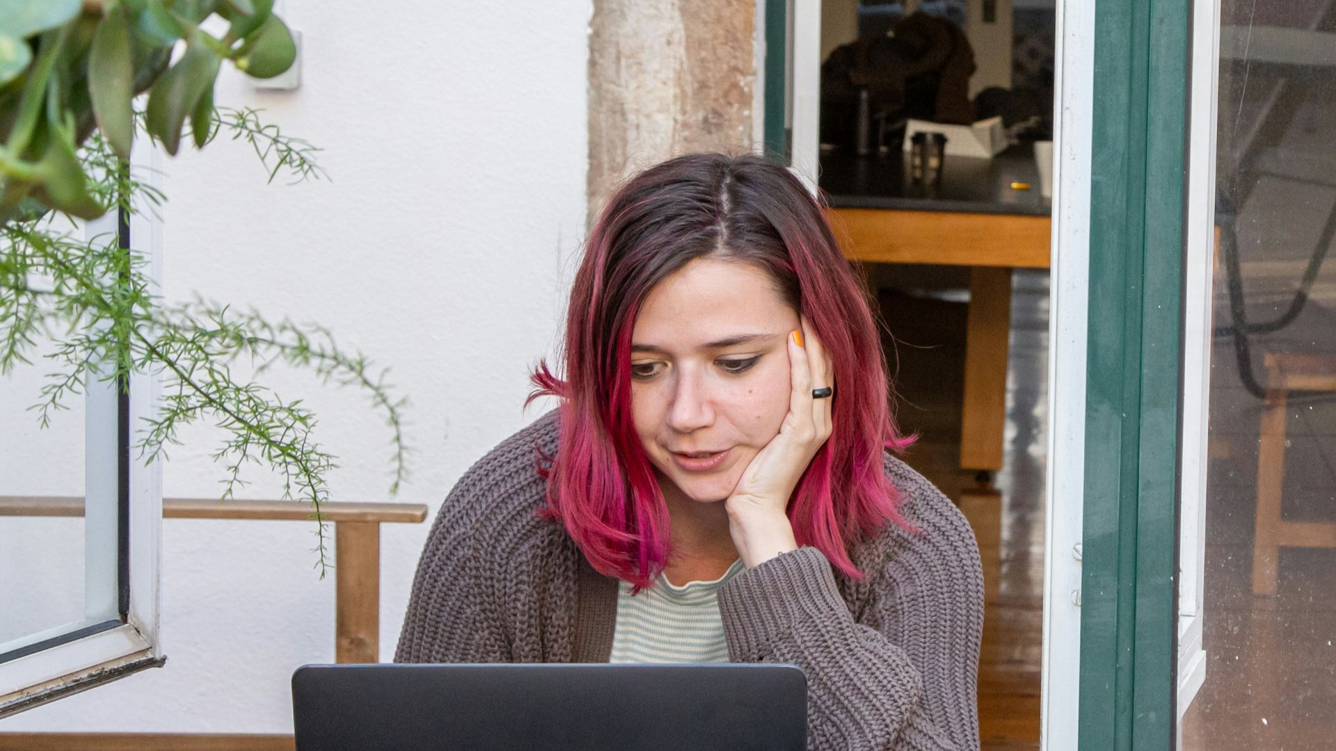 a woman with pink hair is looking at a laptop
