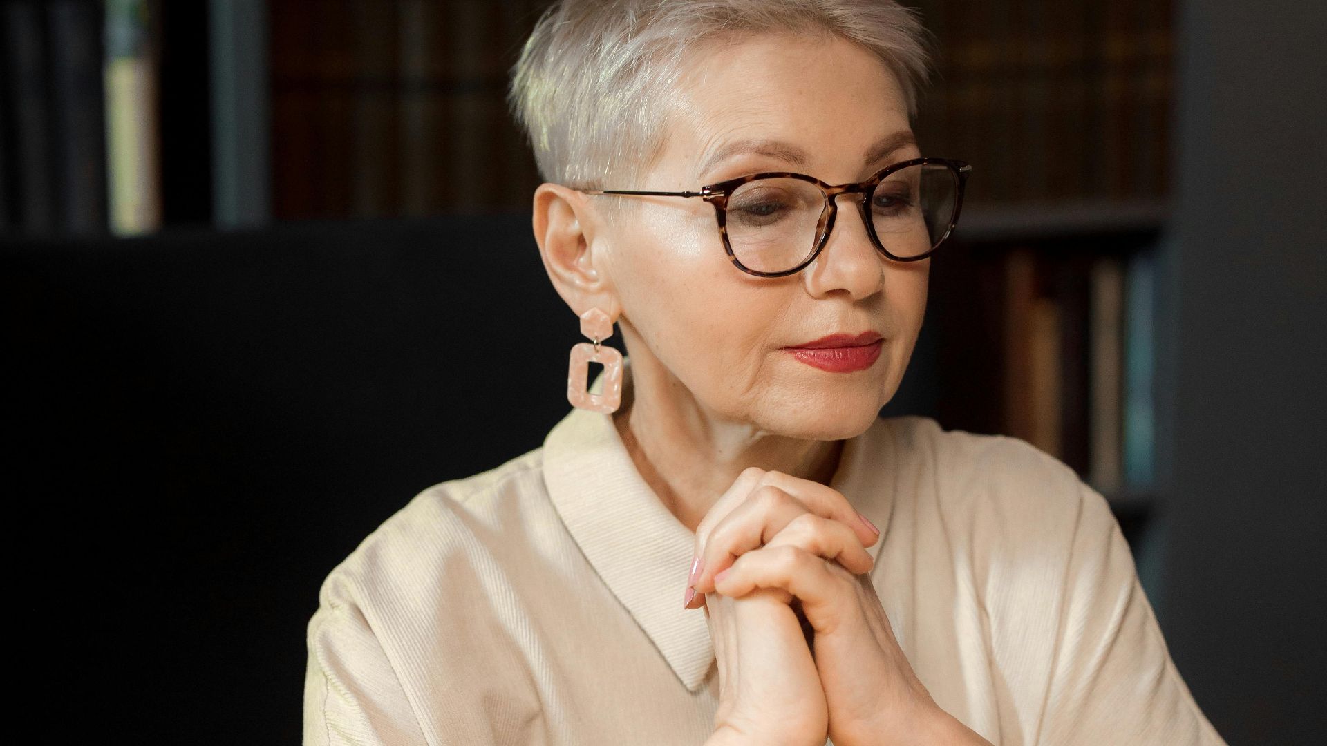 Senior woman in a library setting, reflecting on literary ideas.