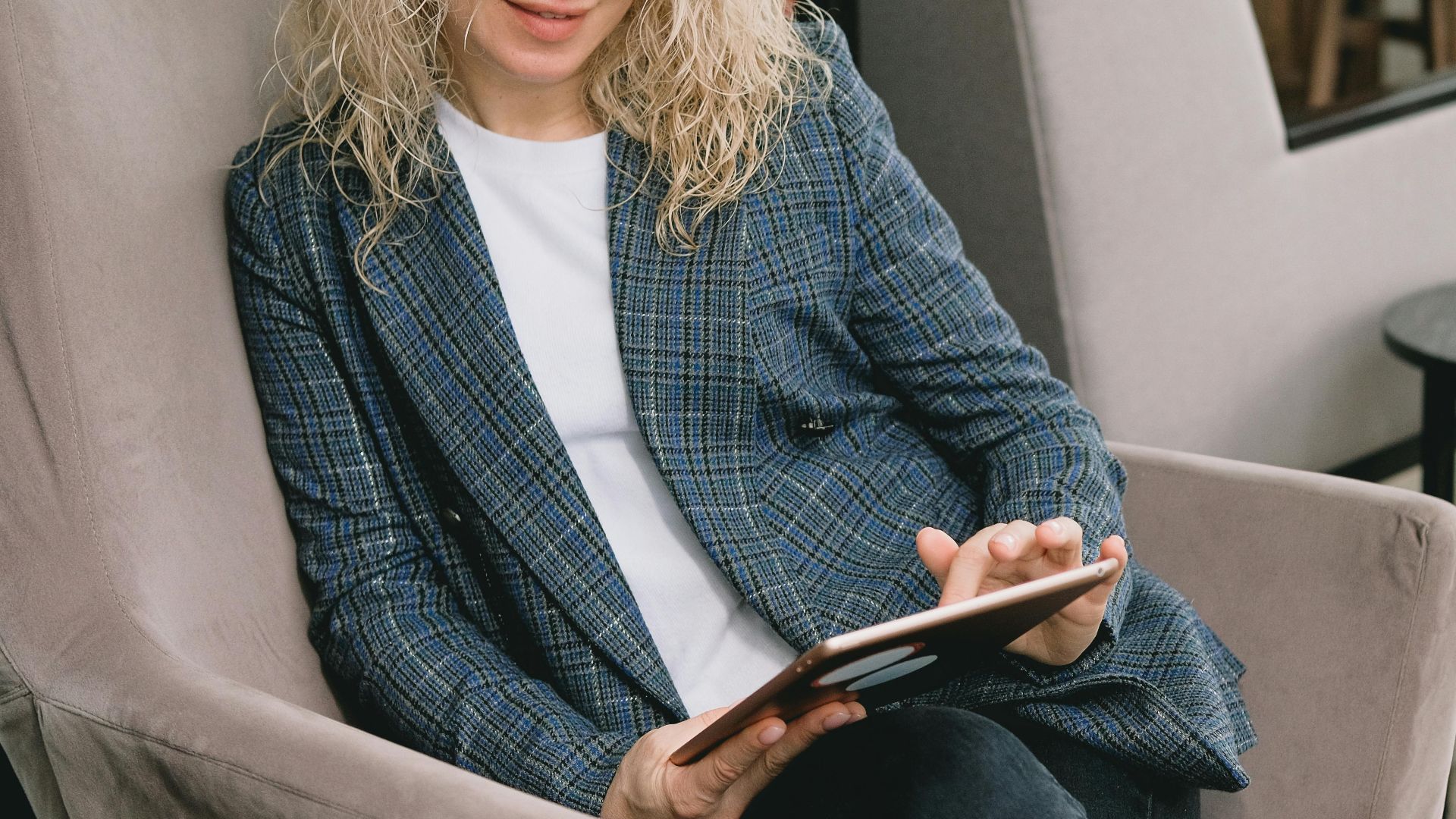 A woman seated indoors using a tablet, enjoying leisure time.