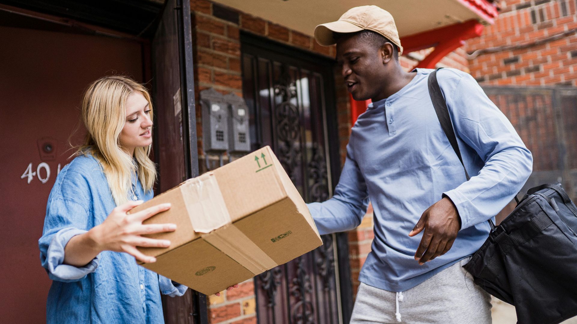 A delivery man handing a package to a woman at her doorstep, emphasizing delivery services.