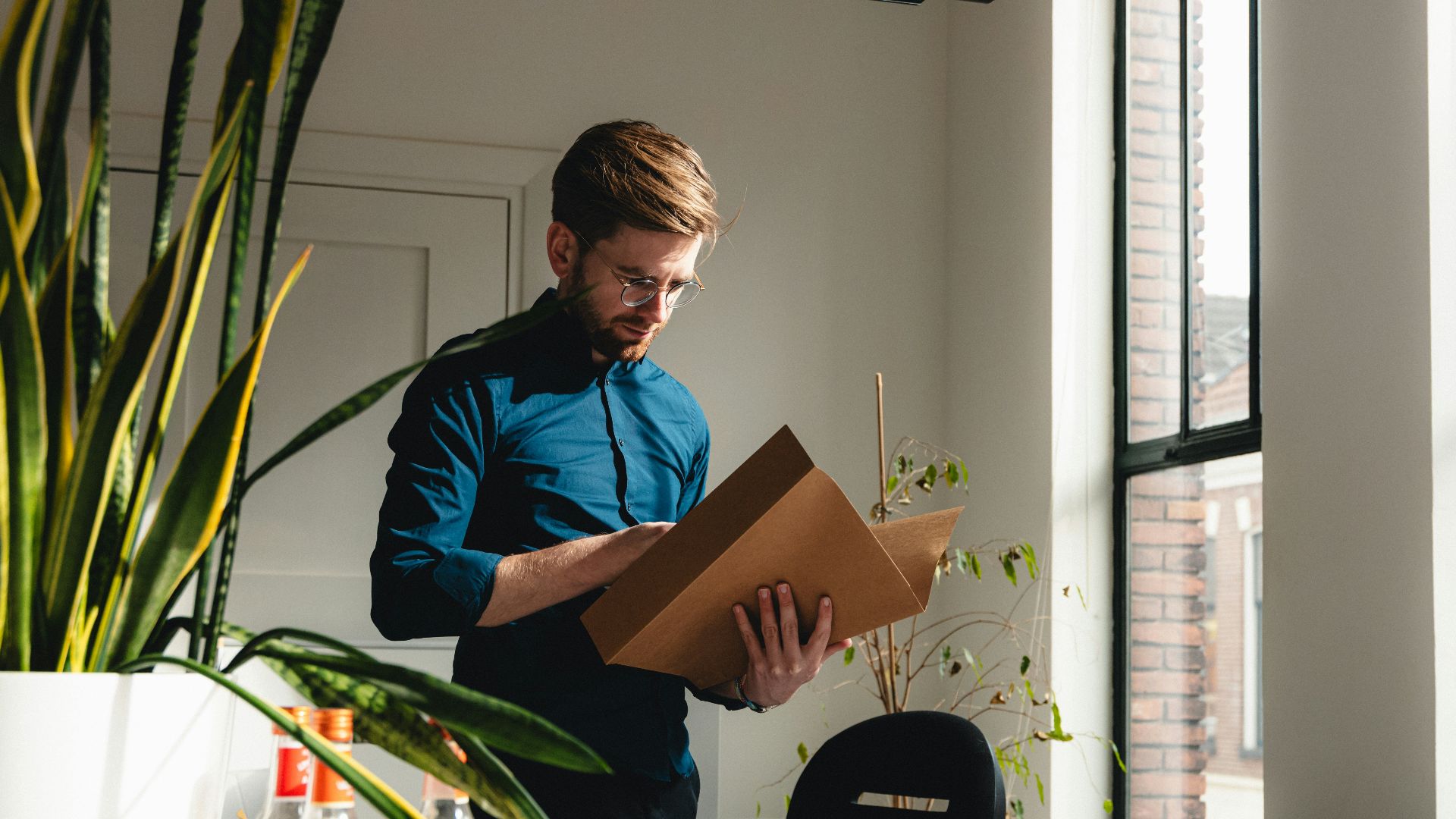 a man standing in an office holding a box