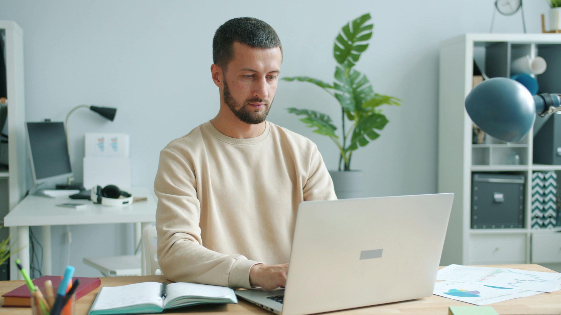 Focused man working on laptop in a bright, modern office setting.