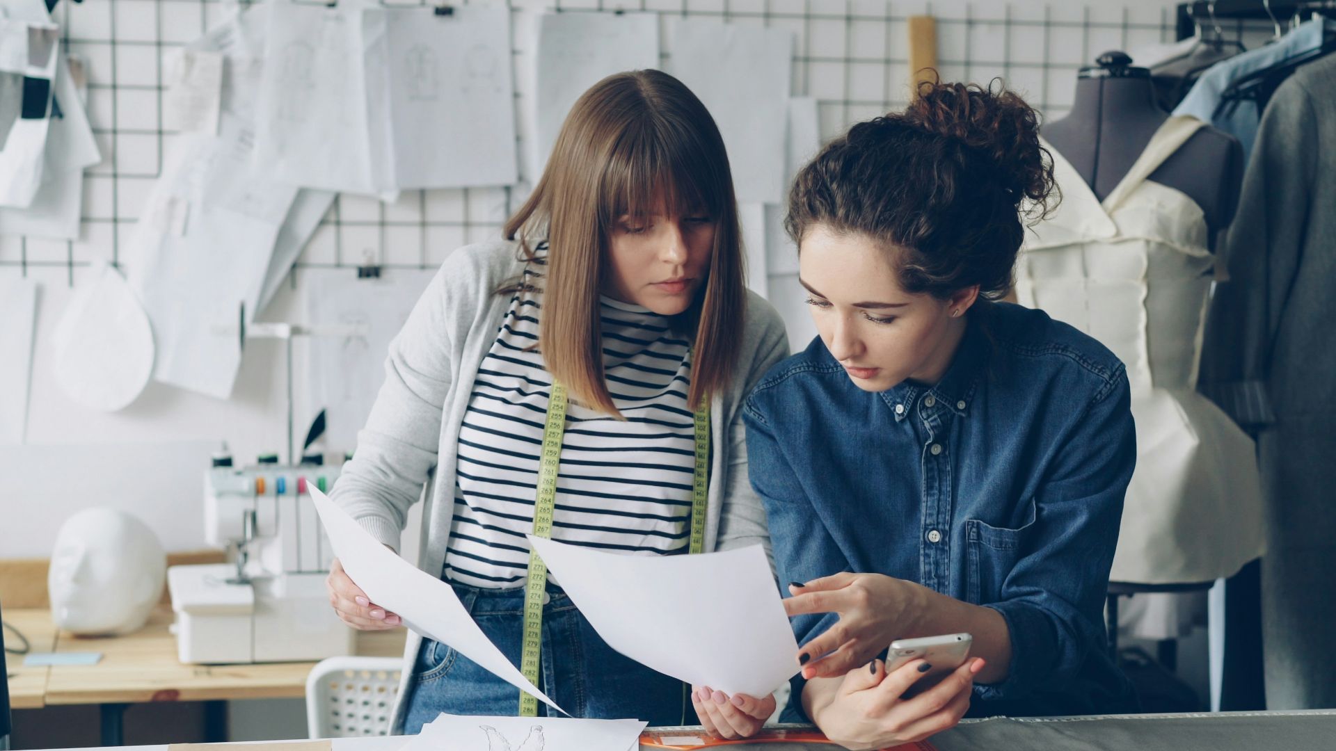 Two designers discuss a paper in a workshop.