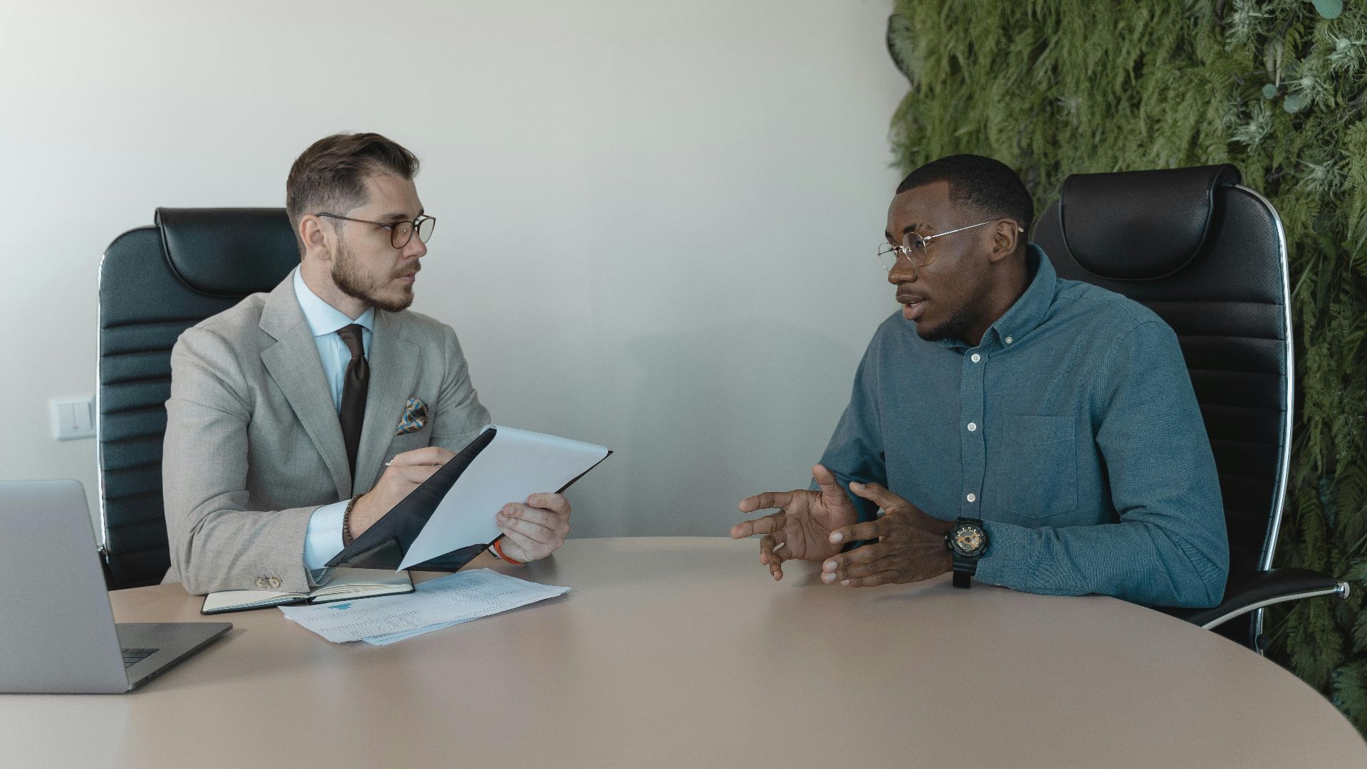 Two businessmen engaged in a discussion during a job interview in a contemporary office environment.