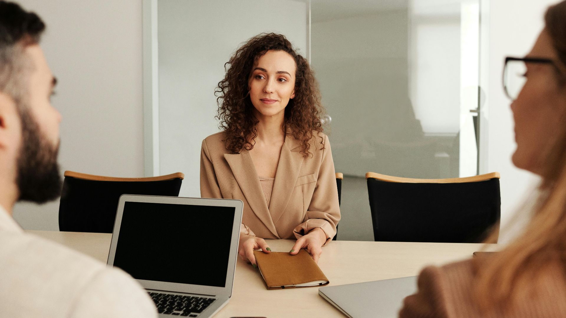 A woman in a business suit participates in a job interview, showcasing professionalism and modern office environment.