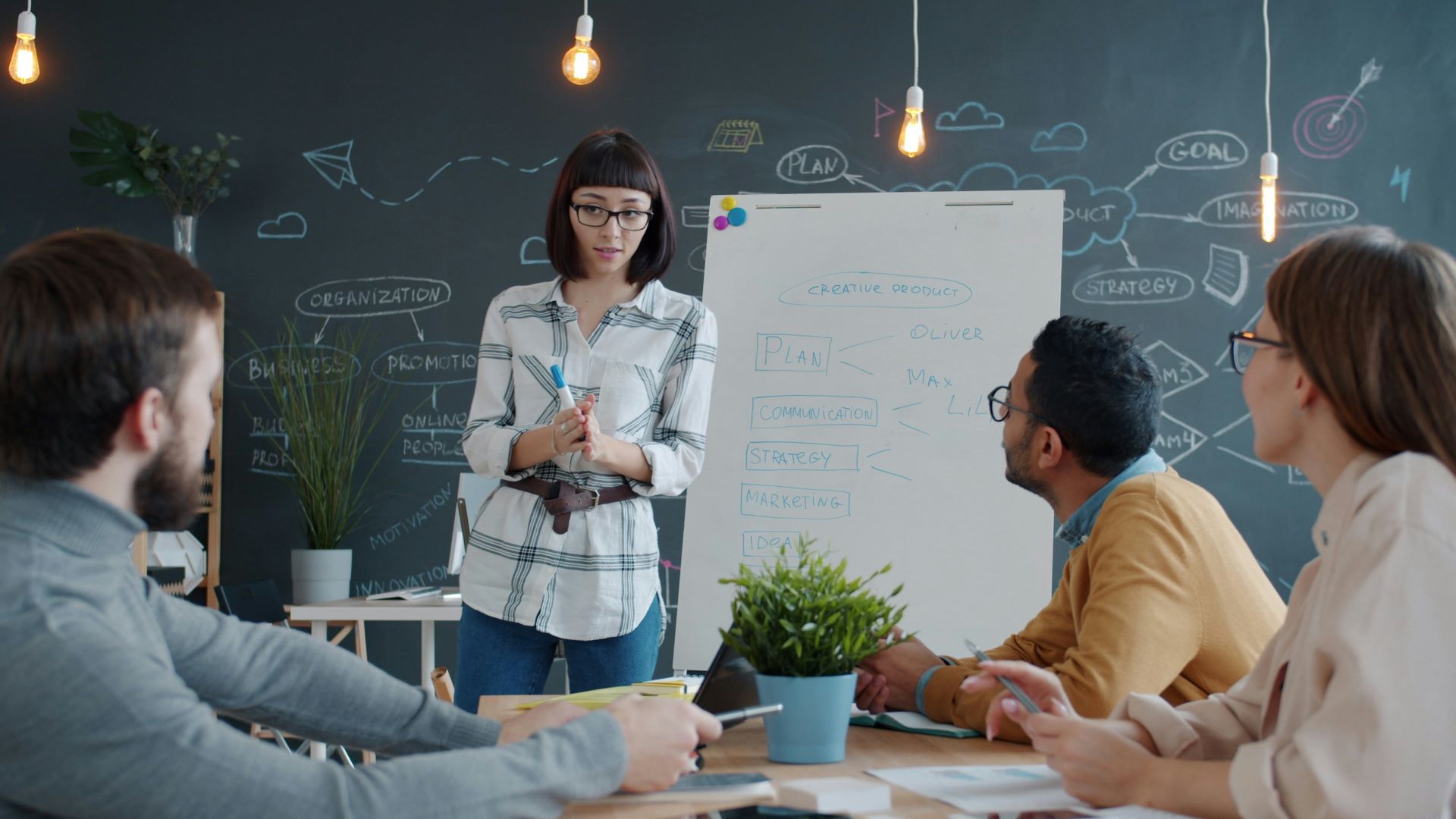 Woman presents to colleagues at a whiteboard meeting.