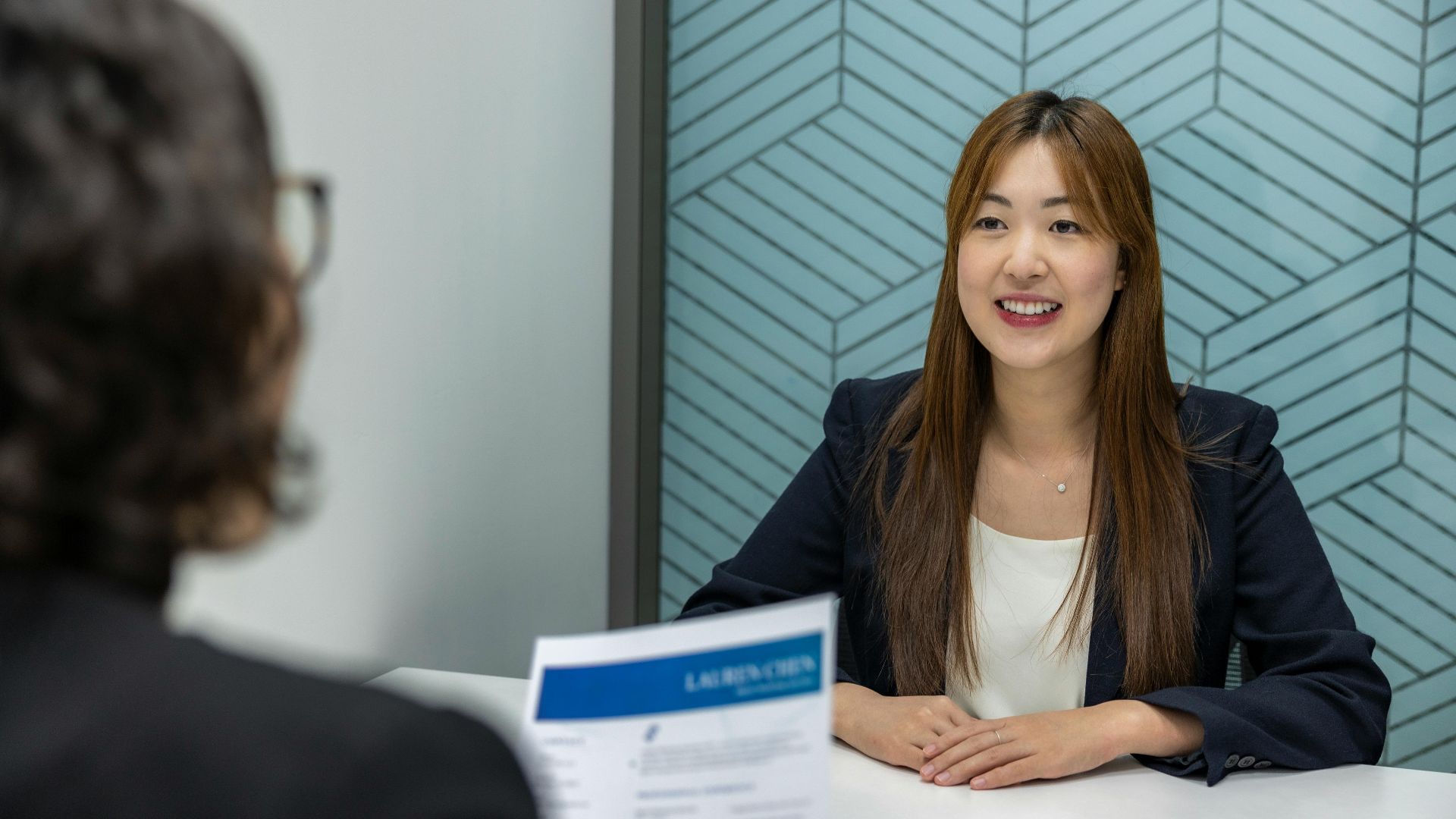 Young woman in a business meeting with an interviewer, showcasing confidence and professionalism.