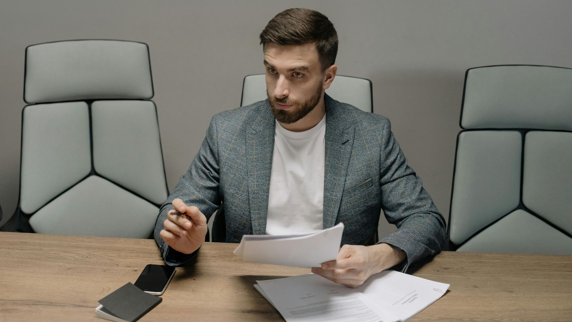 Professional businessman in a suit holding documents during a meeting in an office setting.