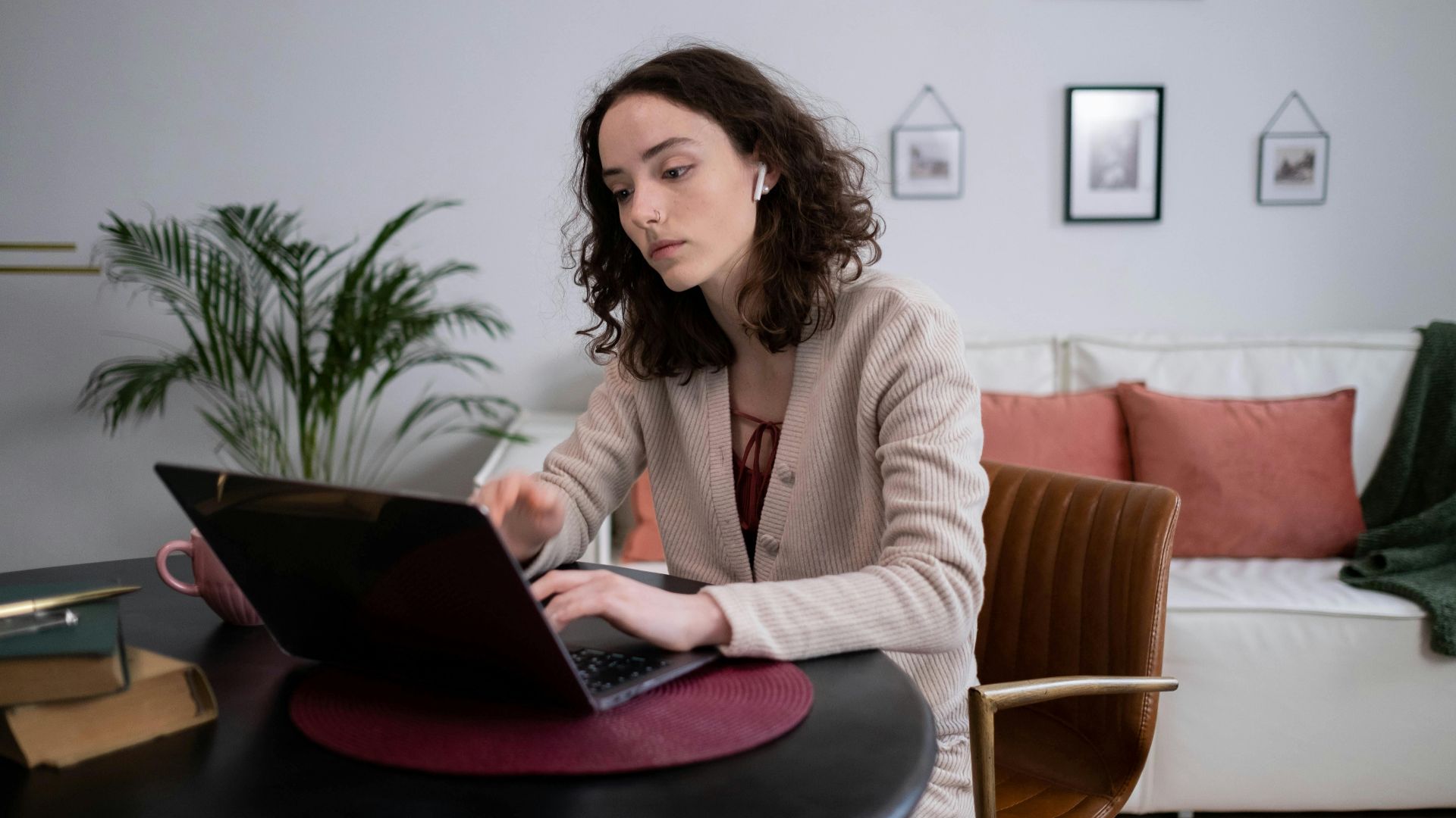 A woman in a cozy home setting working remotely on her laptop, embodying modern digital nomad lifestyle.