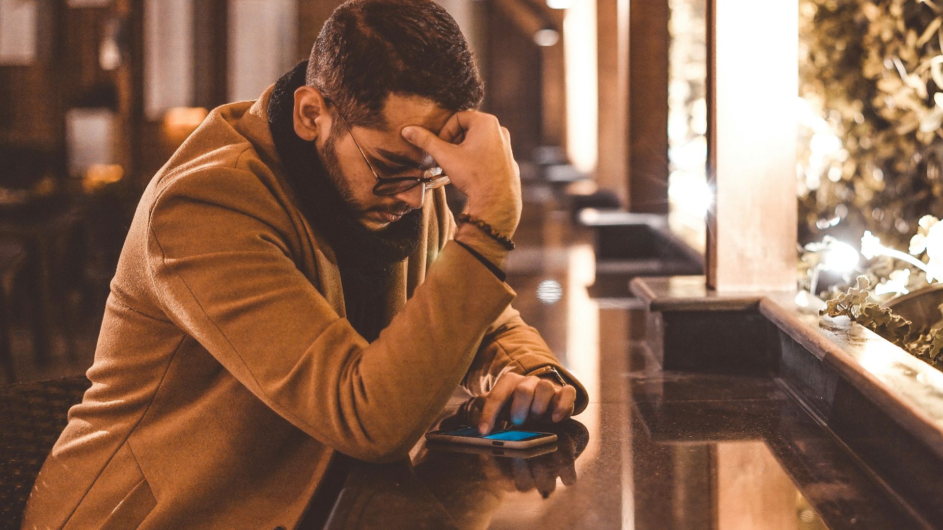 man in brown jacket sitting on brown wooden bench