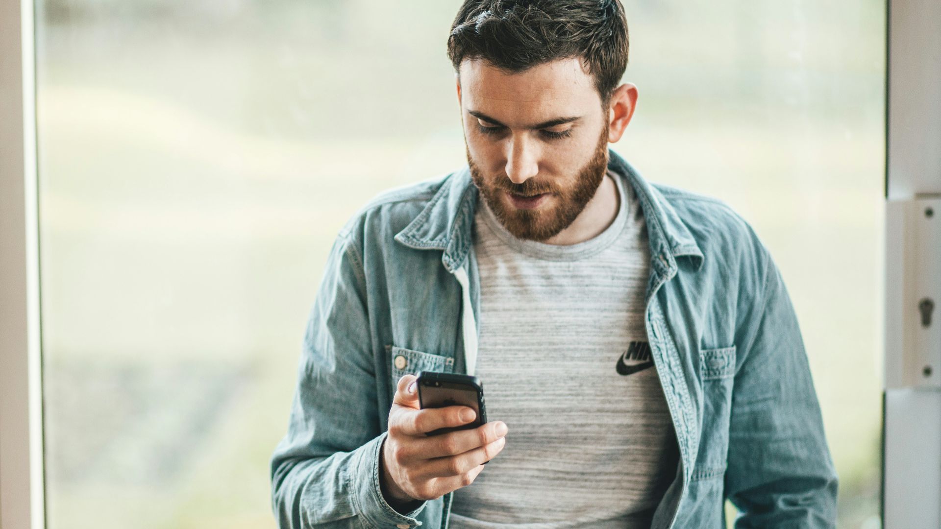 man holding a smartphone near the window