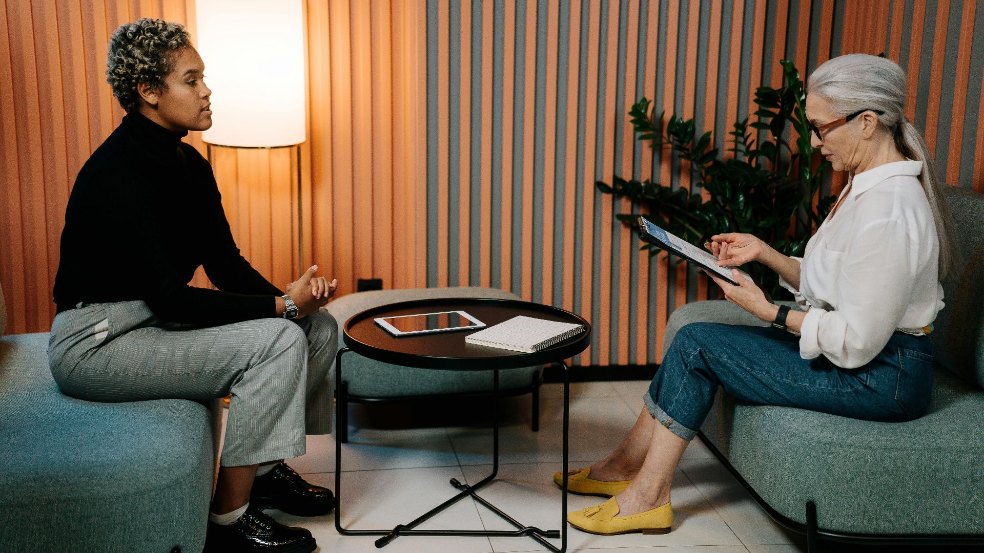Two women engaging in a professional interview setting, using a tablet.