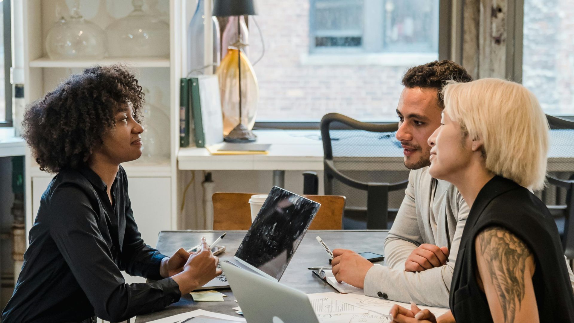 A diverse group of professionals having a meeting at an office table with laptops.