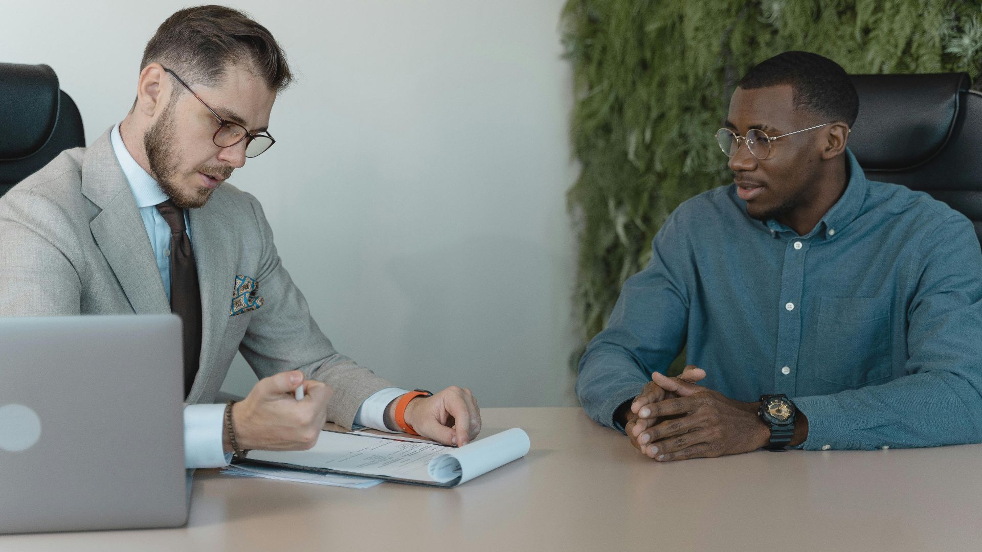 A professional job interview between two men in a modern office environment.