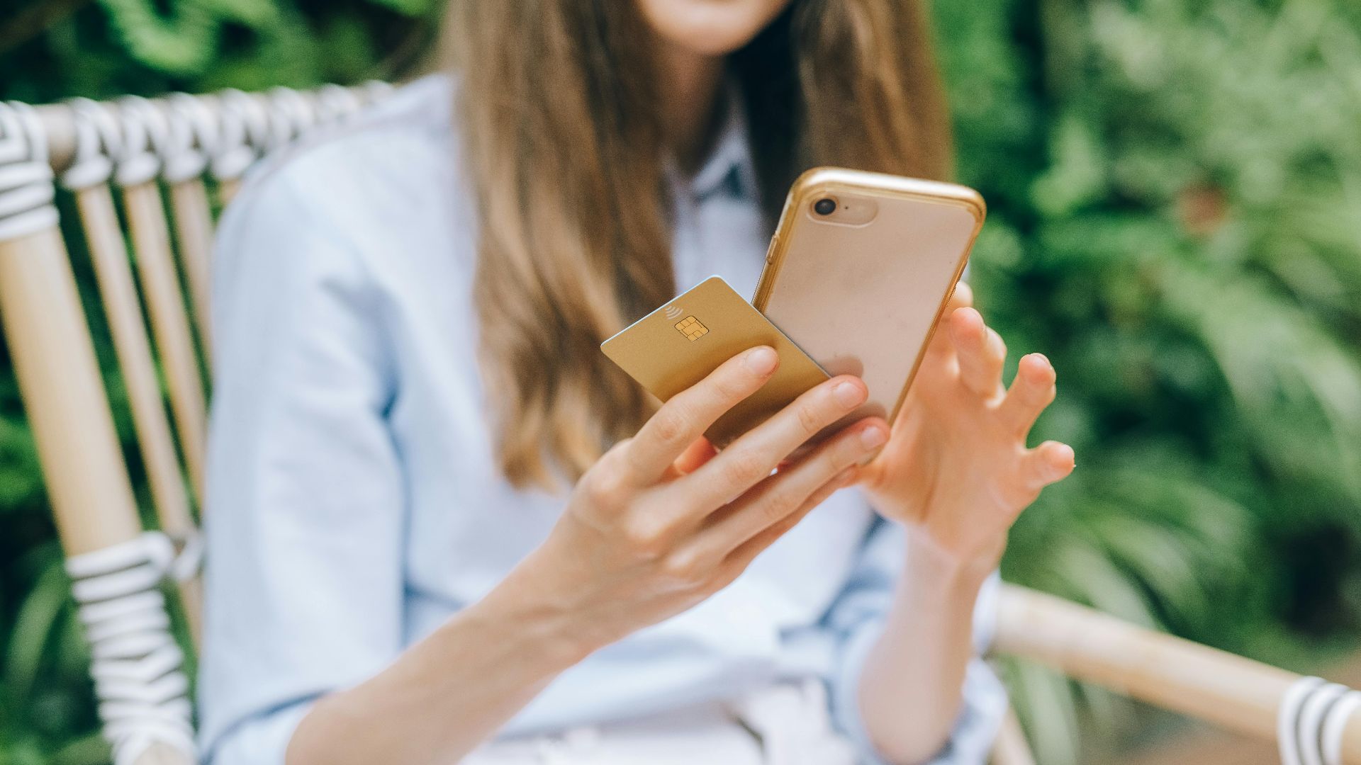 A woman making an online purchase using a smartphone and credit card outdoors.