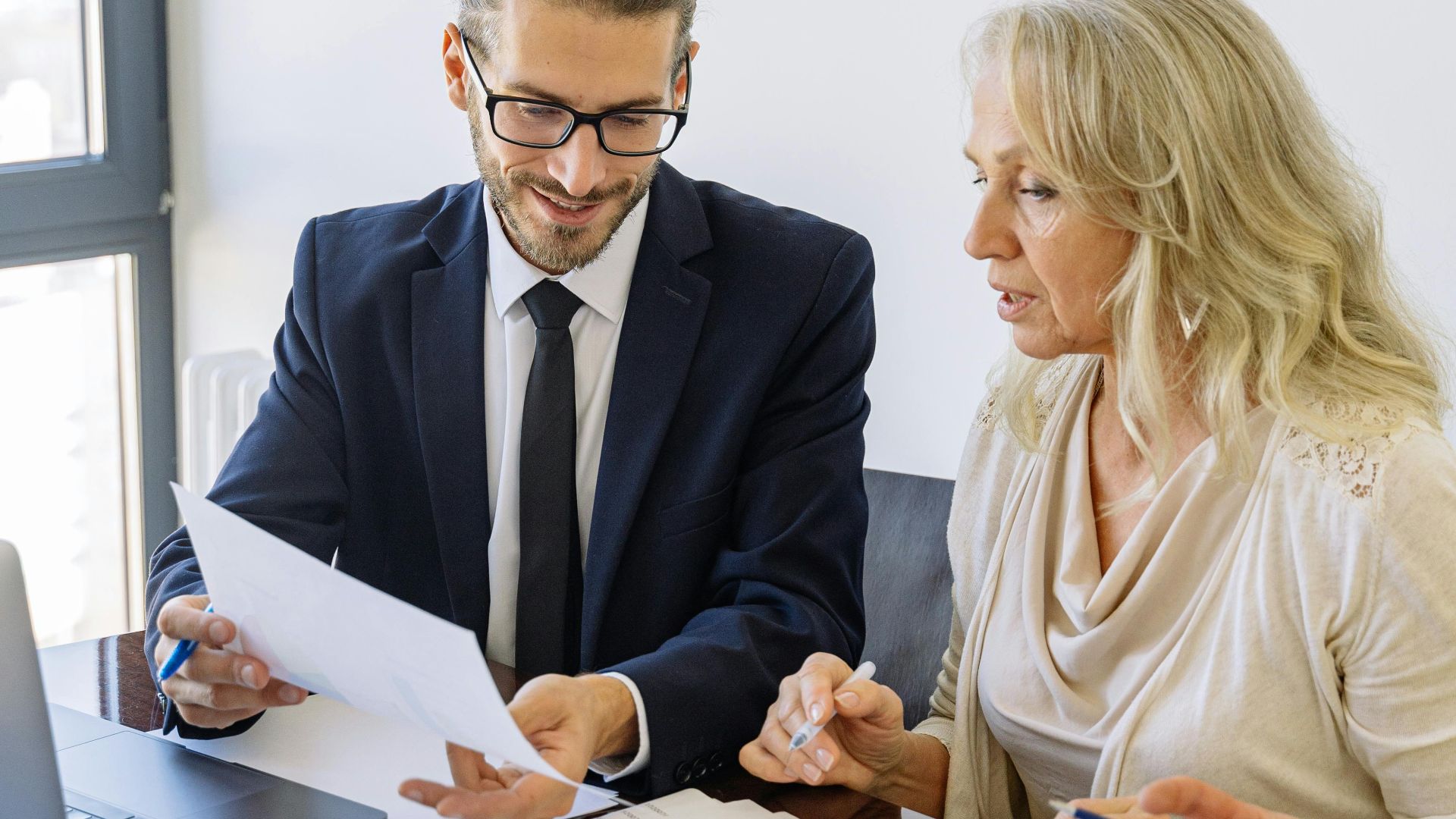 Two business professionals reviewing financial documents and graphs during a meeting.