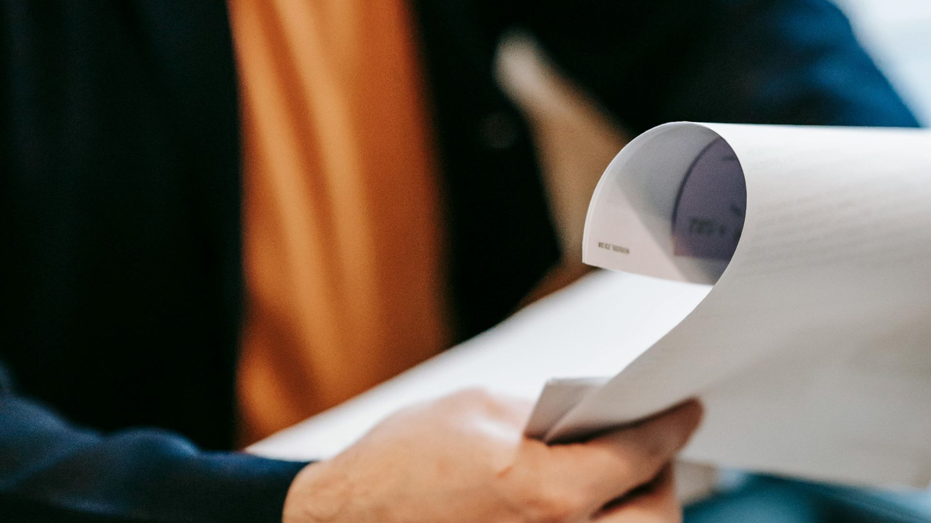 Business professional reviewing important documents indoors. Hands focus, blurred background.