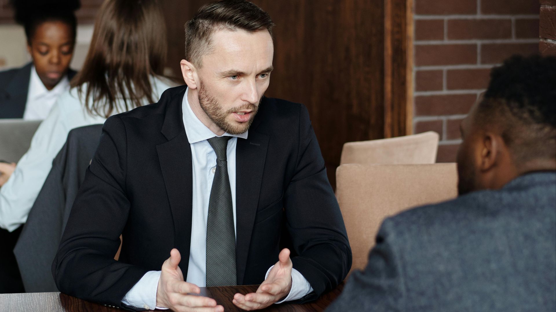 Professionals in suits having a focused business discussion in a stylish café.