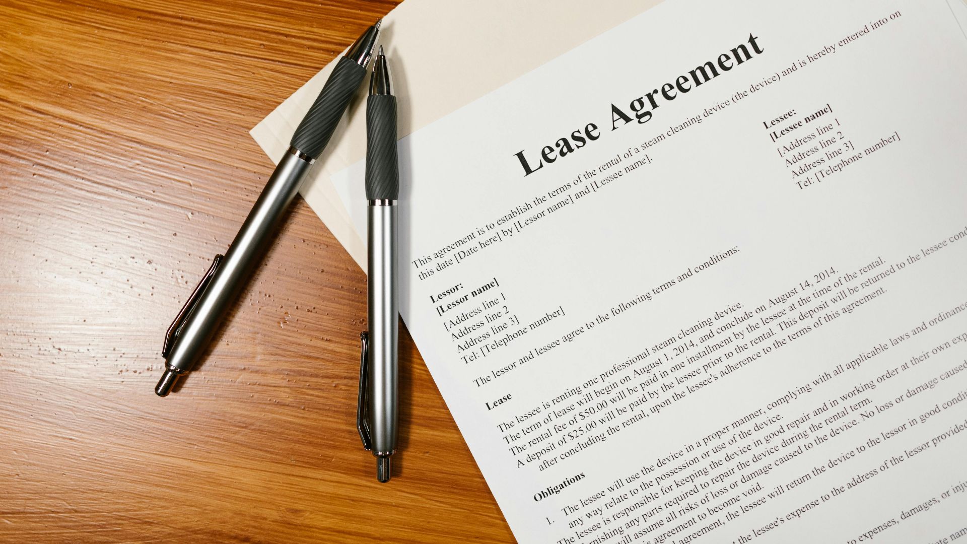 High-angle view of a lease agreement and pens on a wooden desk.