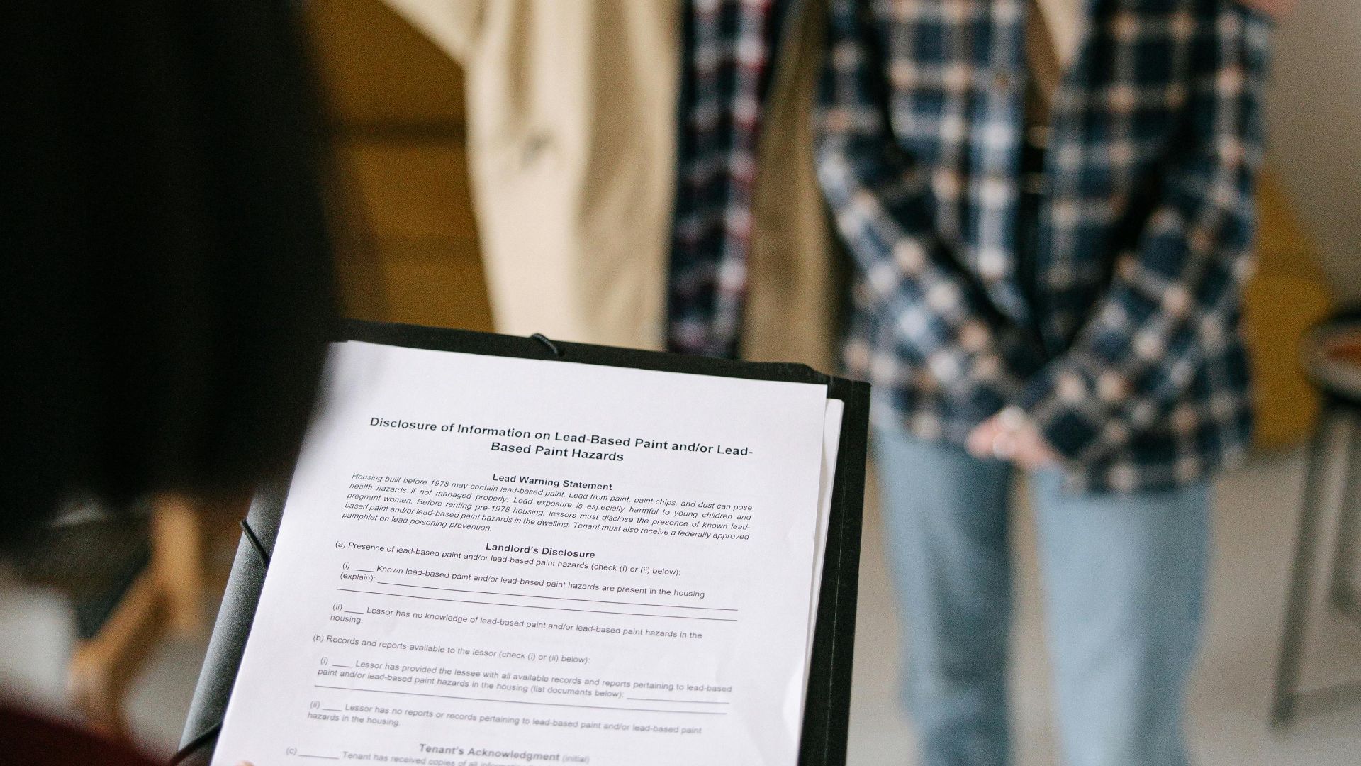 A focused view of a couple discussing a real estate document with an agent in an apartment setting.