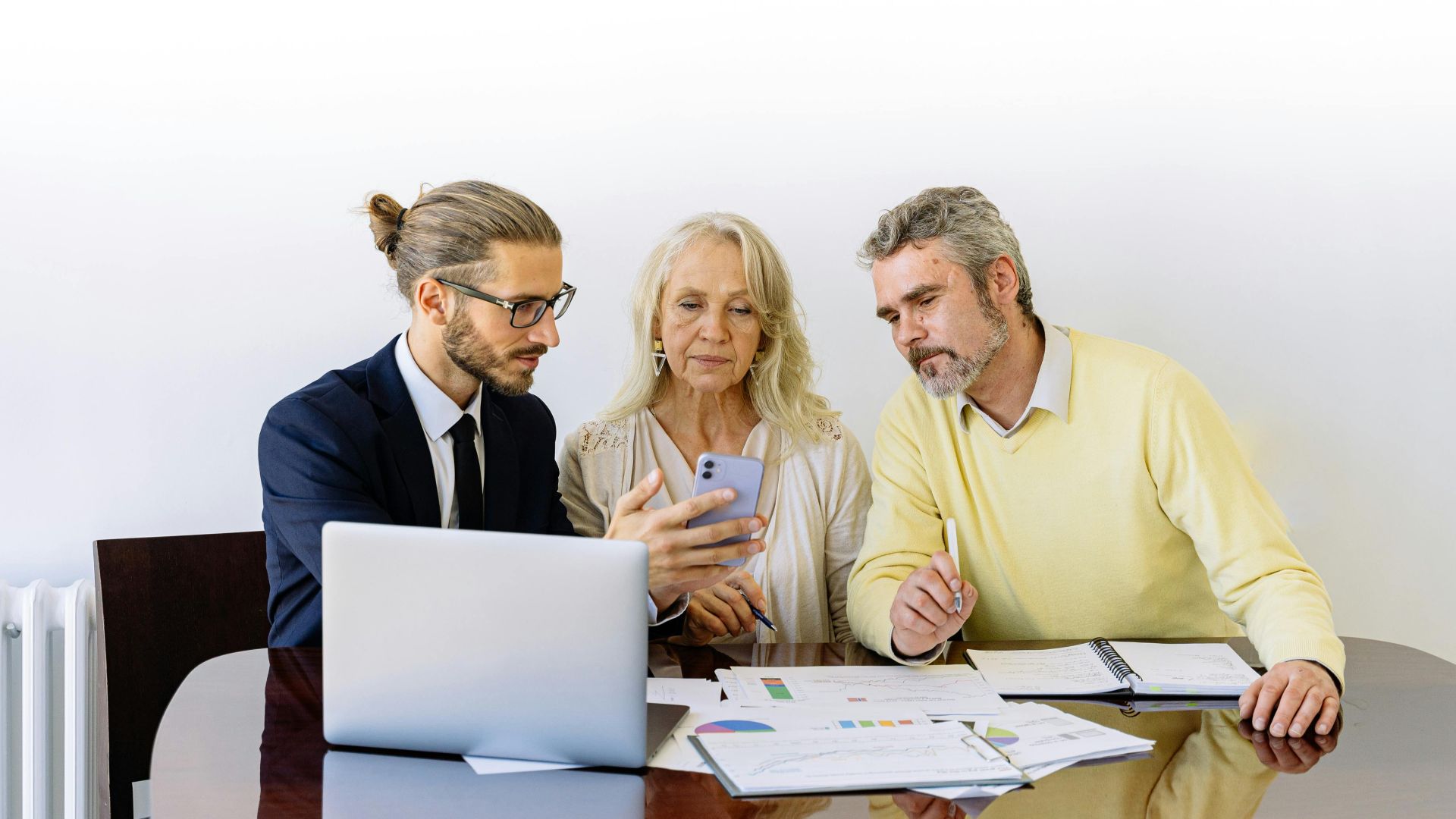 Three individuals collaborating on financial documents during a business meeting.