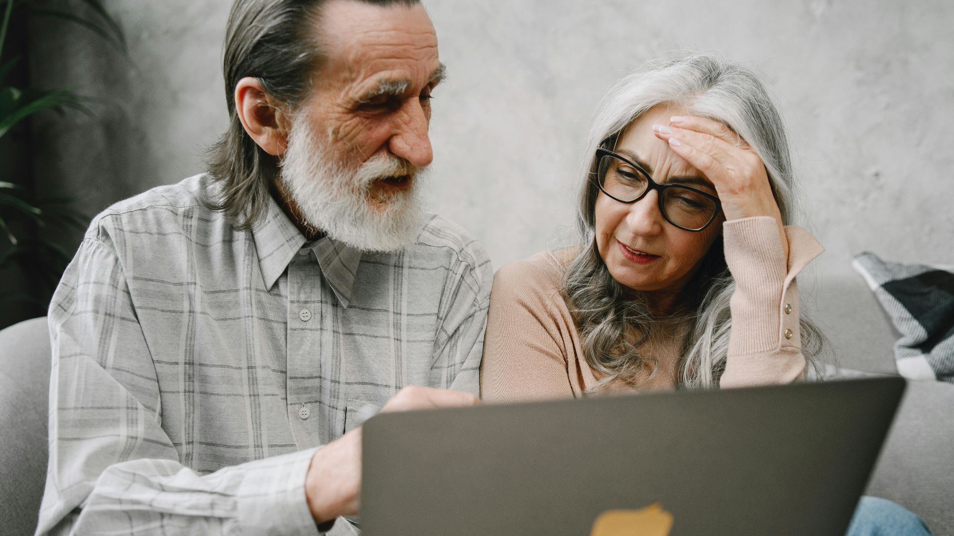 Senior couple using a laptop together at home, engaging in a focused conversation.