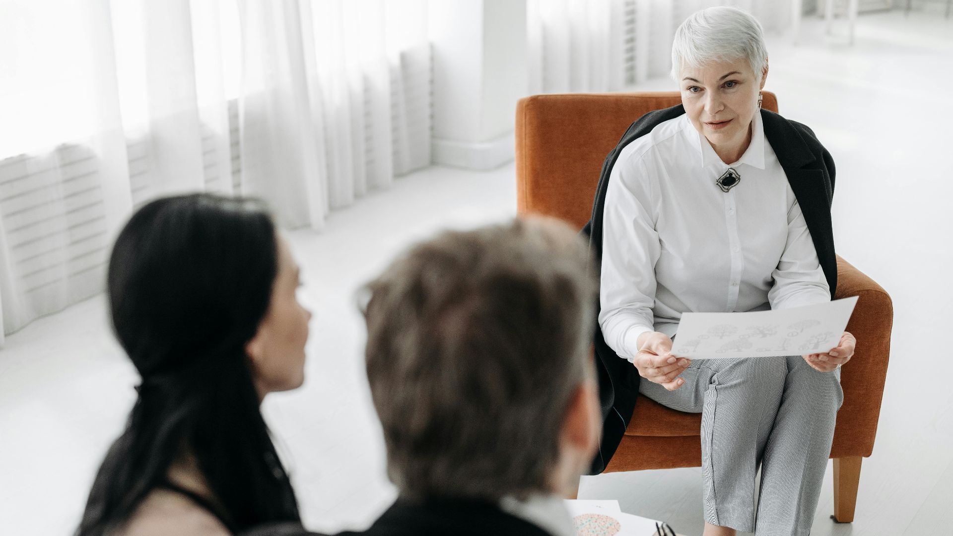 Professional advisor discussing documents with a couple in a modern office setting.
